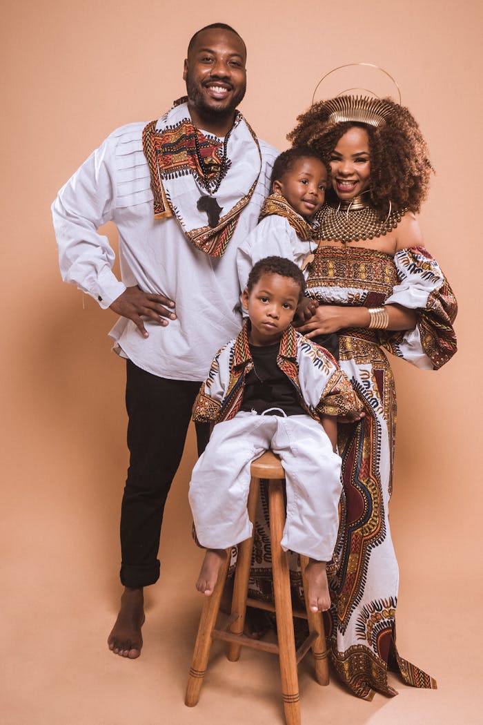 Smiling family in colorful traditional attire, showcasing unity and culture in a studio portrait.