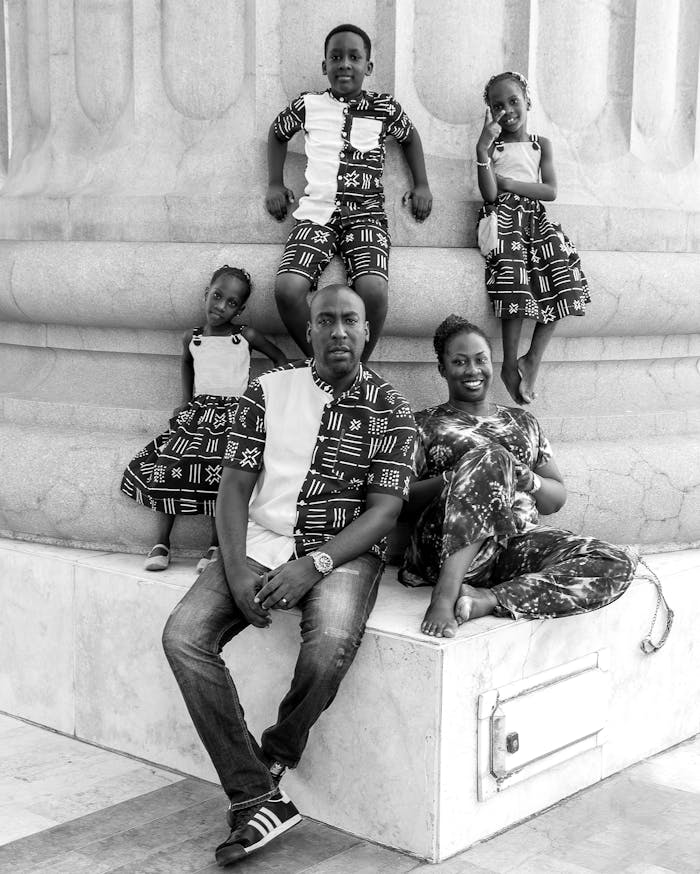 A joyful family of five posing by a large column, showcasing togetherness and love.
