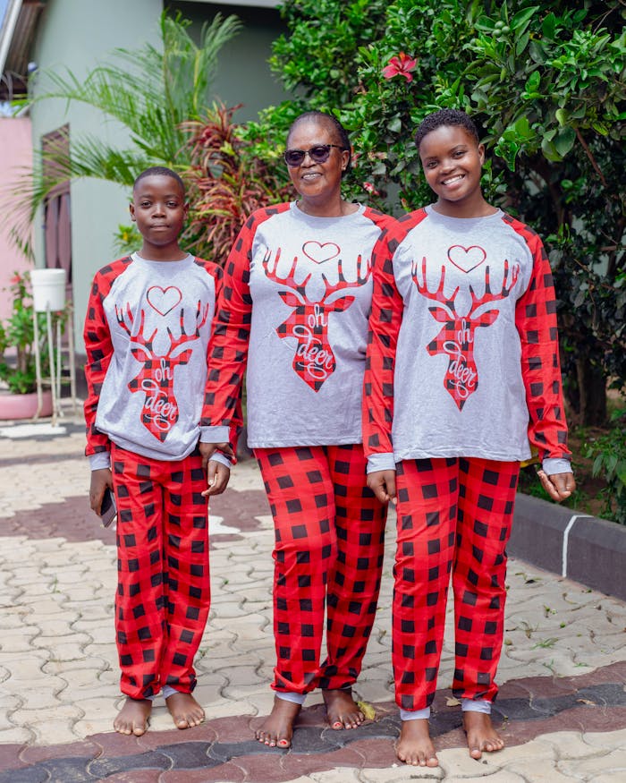 Family wearing matching Christmas pajamas with deer design, enjoying outdoor time together.