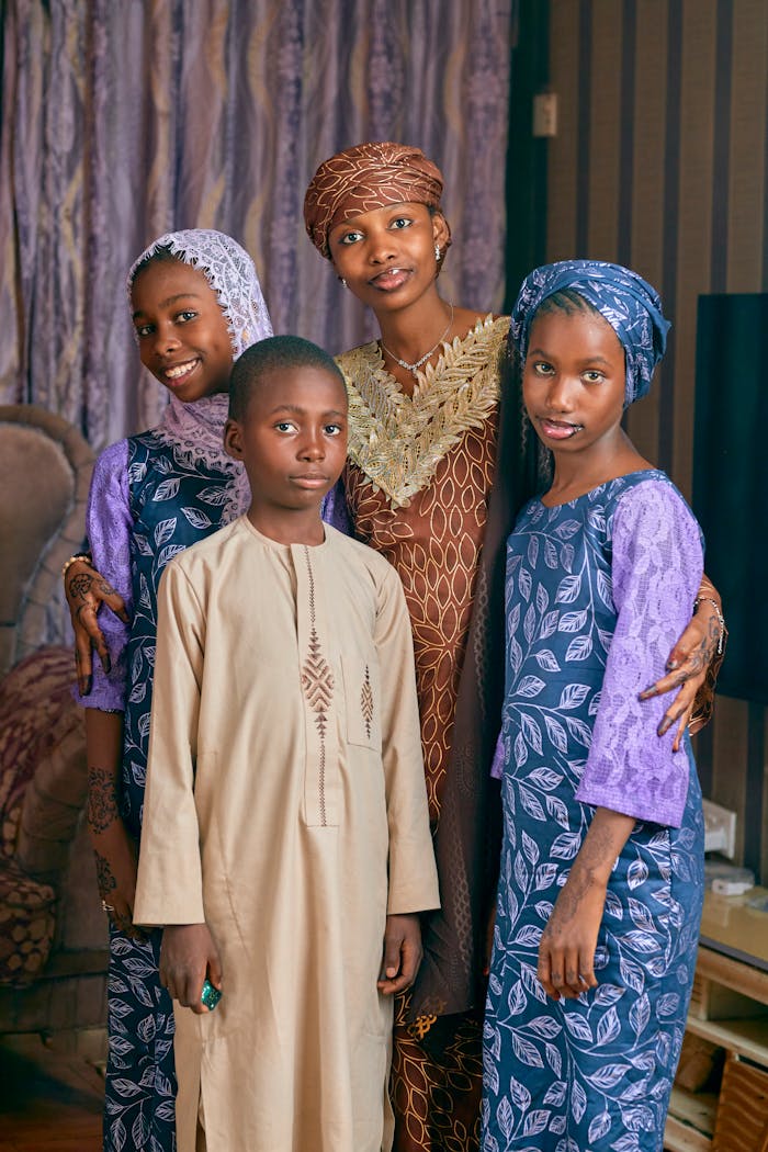 Smiling family in traditional African attire with detailed patterns indoors.