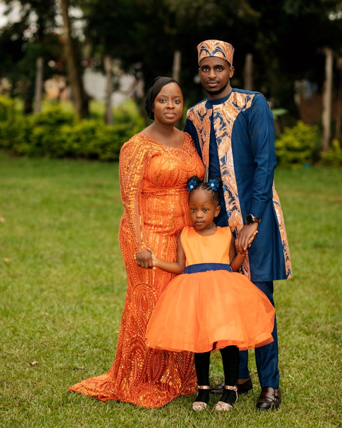 Family portrait with vibrant traditional African attire in a lush garden setting.