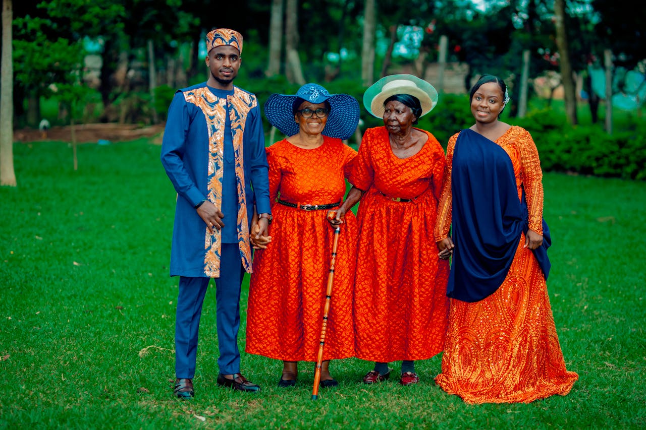 Family in vibrant traditional African attire posing happily in a lush green park.